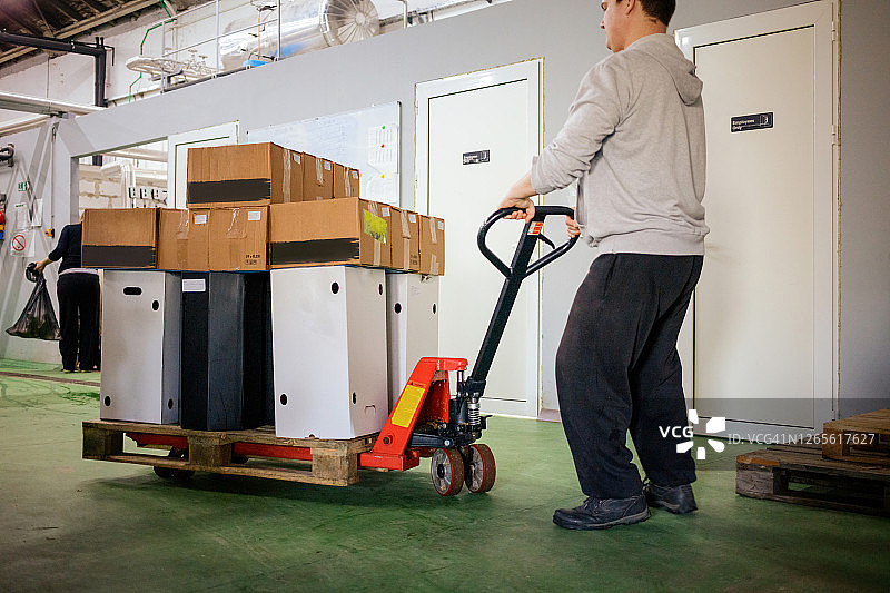 年轻人在啤酒厂仓库里推动托盘车图片素材