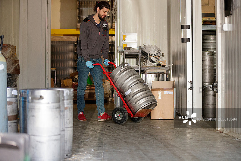 啤酒厂工人用手推车运送铝桶图片素材