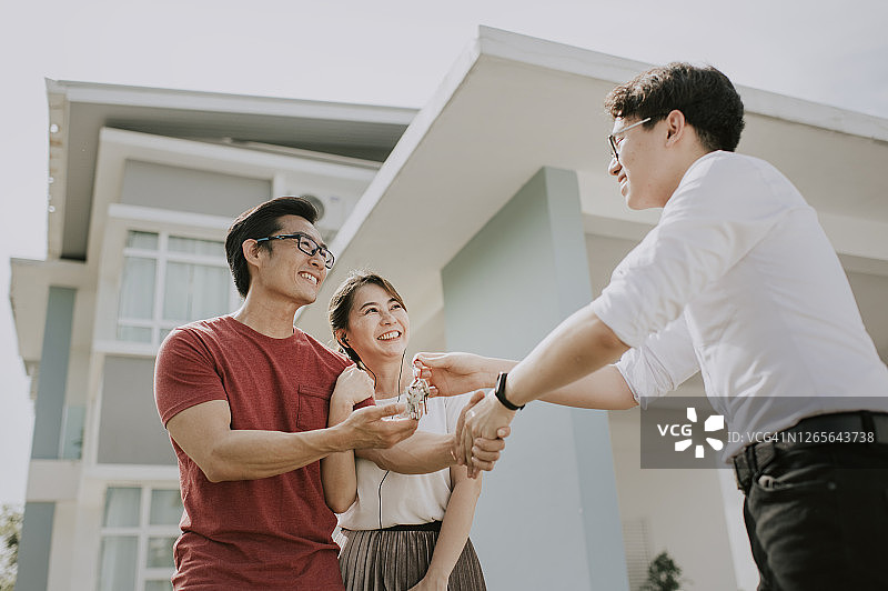 一个中国家庭搬进新家，从房地产经纪人手中接过钥匙图片素材