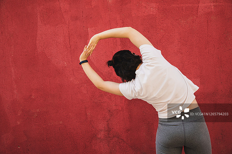 在红墙前伸展的亚洲女人图片素材