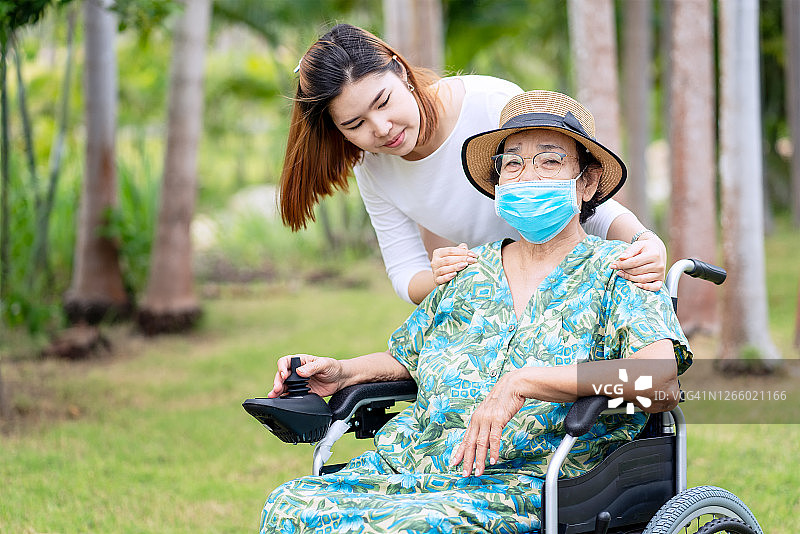 女人在公园帮助和照顾坐在电动轮椅上的病人图片素材