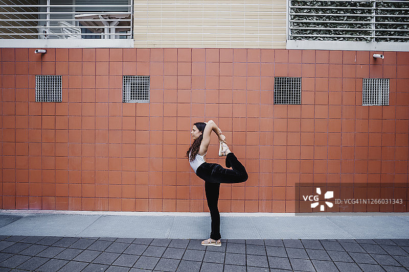 年轻女人在城市人行道上练习瑜伽图片素材