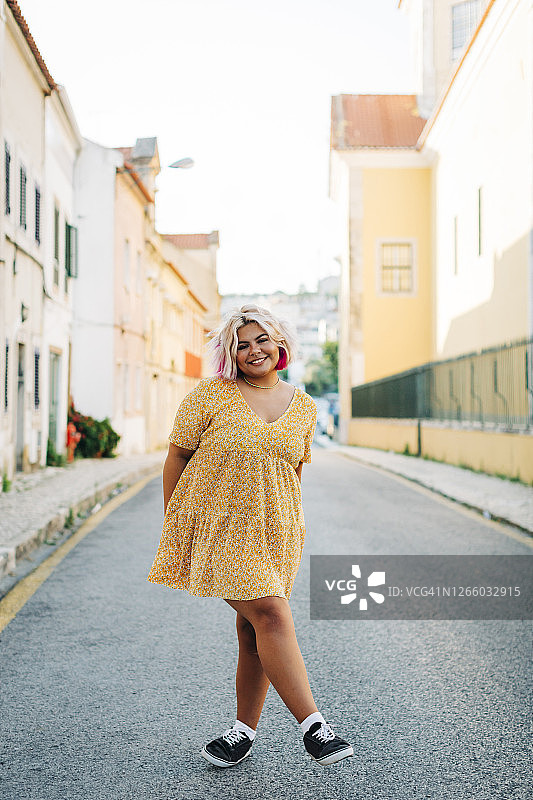 在路上交叉双腿站立的微笑大码女人图片素材