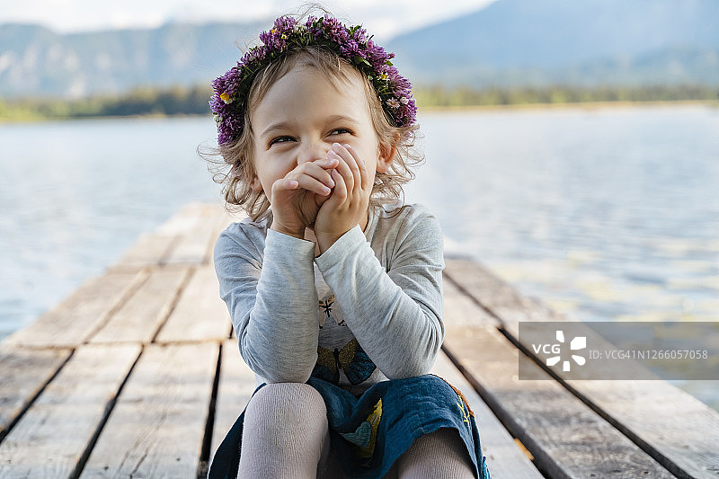 可爱女孩戴着头饰在湖边码头上欢笑特写图片素材