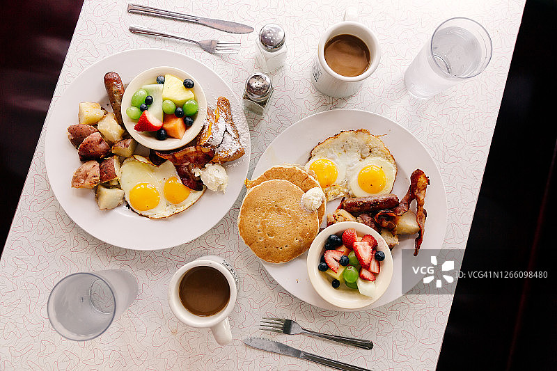 俯视：传统美式餐厅的早餐，包括煎饼、法式吐司、煎蛋、培根和水果图片素材