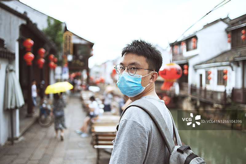 戴防护口罩的男子站在中国传统街道上图片素材