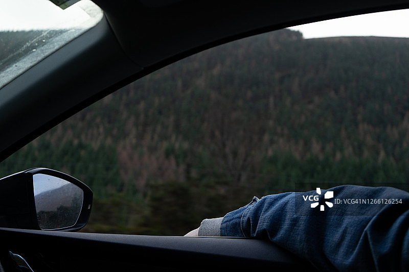 一位穿着牛仔夹克的乘客将手臂伸出窗外图片素材