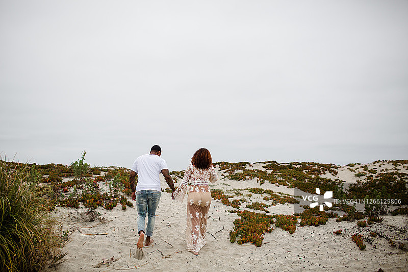 在海滩上牵手散步的混血夫妇图片素材