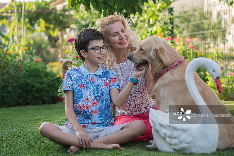 母亲和儿子坐在后院和她的狗玩耍图片素材