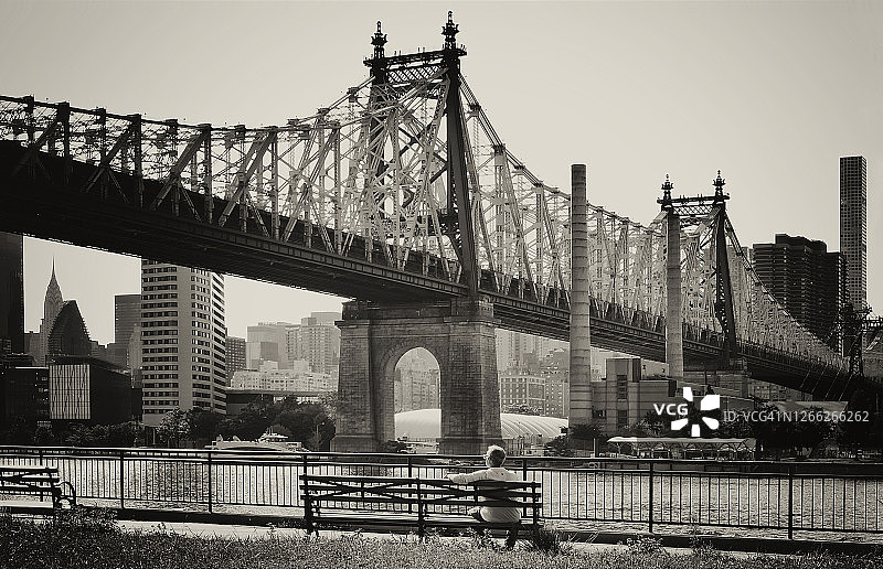 第59街大桥：坐在萨顿广场公园“曼哈顿长椅”上俯瞰昆斯伯勒大桥的人图片素材