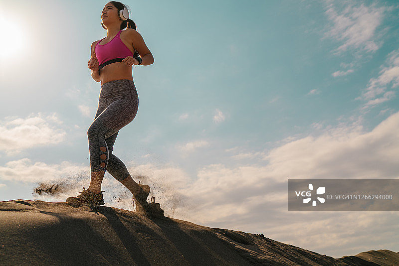 在炎热晴天沙丘上跑步的女运动员图片素材