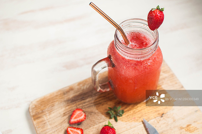草莓冰沙与完整和切片的草莓在砧板上图片素材