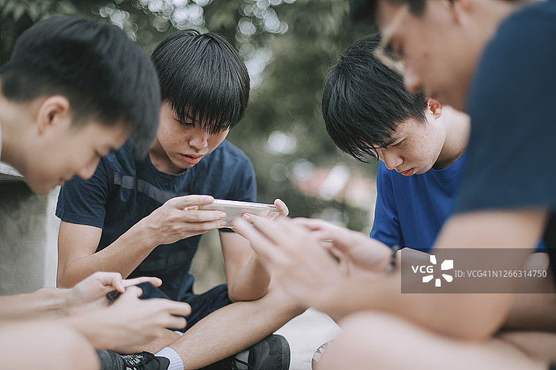 一群中国青少年在篮球场用手机玩手游（Gen Z）图片素材