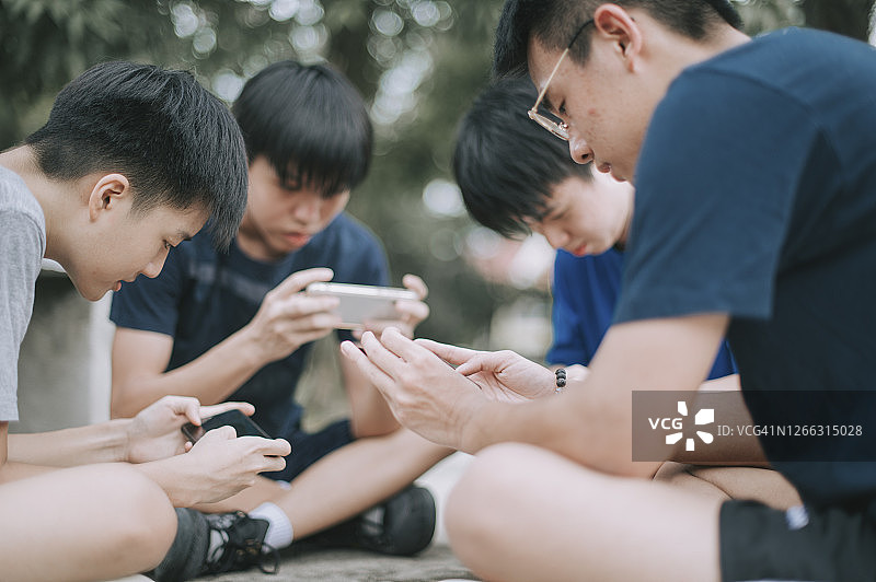 一群中国青少年在篮球场用手机玩手游（Gen Z）图片素材