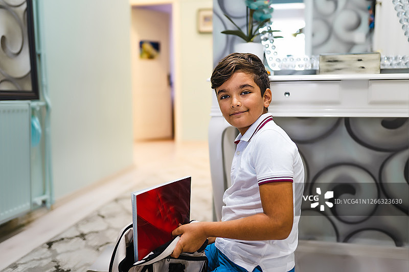 小学生将书本放入背包图片素材