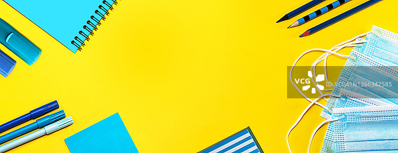 黄色背景上的学习用品和医用口罩图片素材