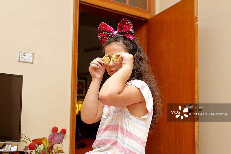 年轻女孩用圆形饼干遮住眼睛，看向镜头图片素材