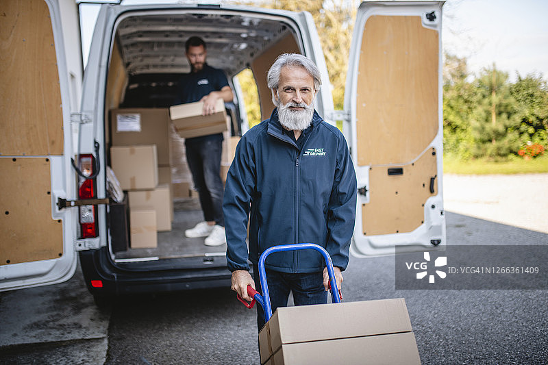 胡须快递员手推车搬运包裹图片素材