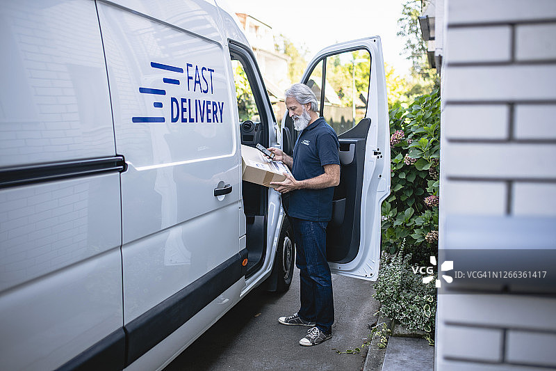 拿着包裹并检查扫描数据的男性送货员图片素材