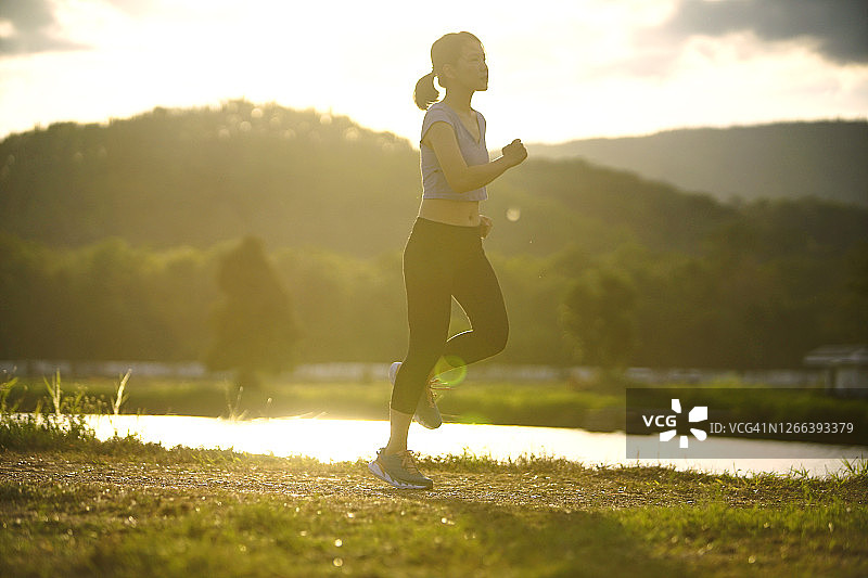 广角亚洲运动女孩在乡村阳光下跑步和慢跑图片素材