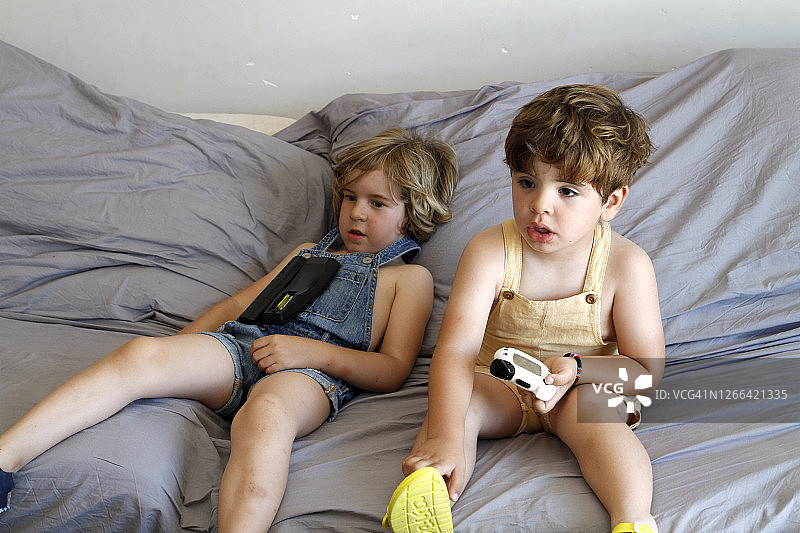 两个小男孩躺在沙发上看电视图片素材