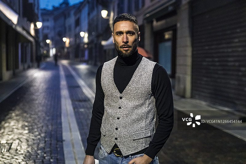 晚上在意大利小镇街道上穿着考究的年轻男子肖像图片素材