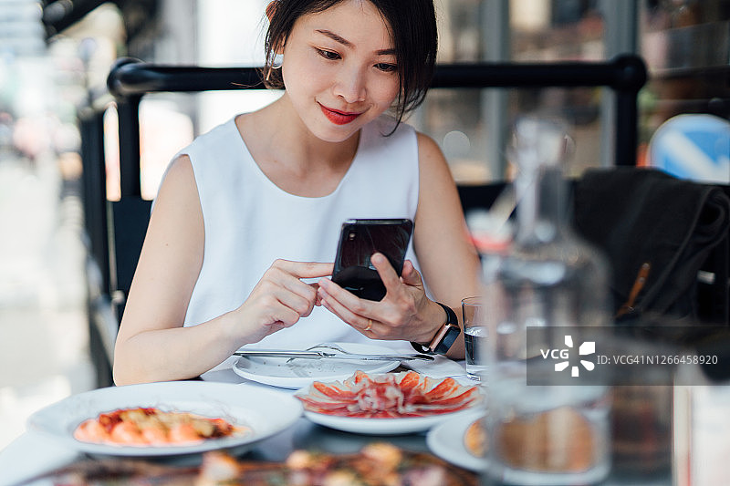 在户外餐厅使用手机的年轻漂亮女子图片素材
