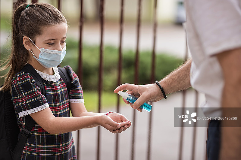 男人在户外为女学生的手消毒图片素材