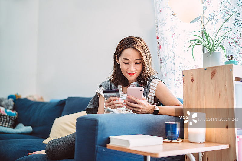 年轻的亚洲女性在家用智能手机在网上购物图片素材