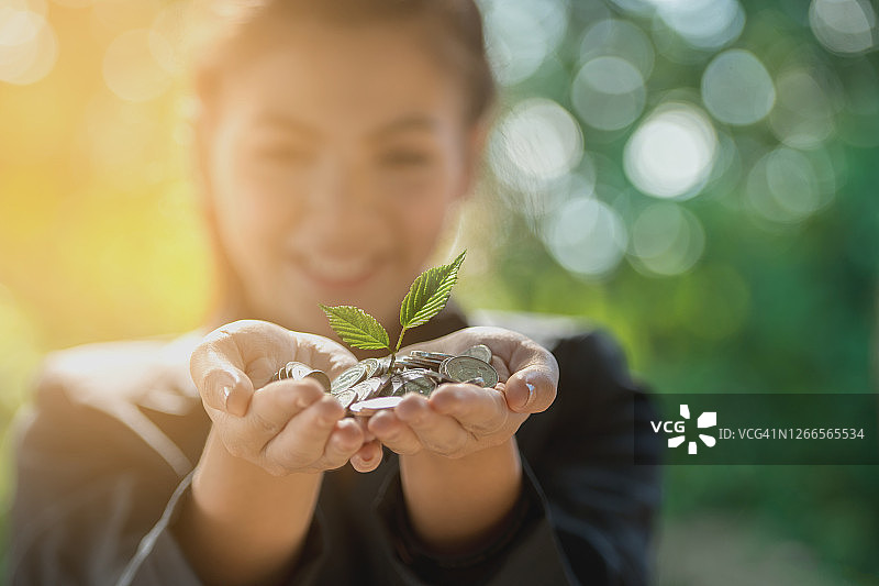 手持硬币中生长的摇钱树概念，散景背景图片素材
