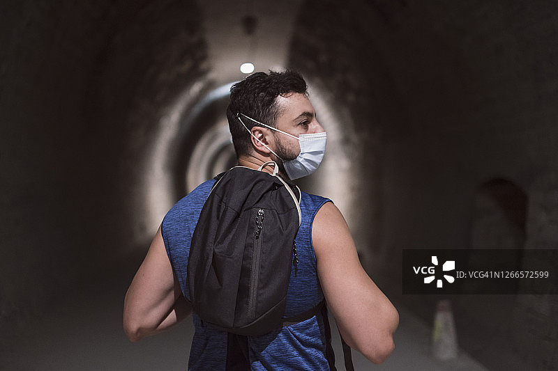 背包男士穿过黑暗隧道，象征疫情或污染带来的沮丧图片素材