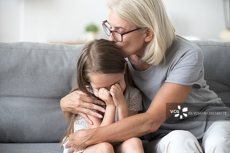 奶奶拥抱沙发上沮丧的孙女图片素材