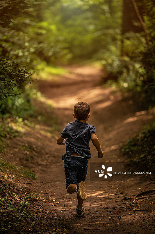 男孩在森林的土路上奔跑图片素材