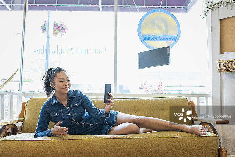 年轻女人在沙发上玩手机图片素材