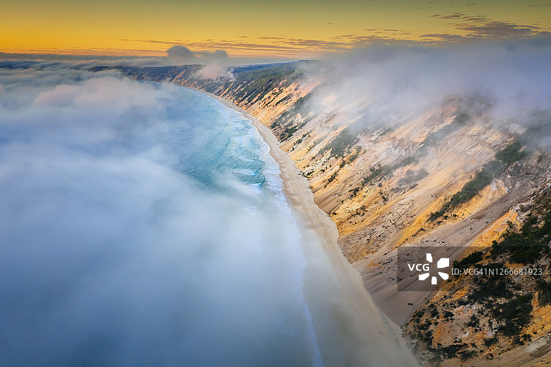 日出时分，彩虹海滩壮观的彩色沙滩航拍，低云覆盖海洋图片素材