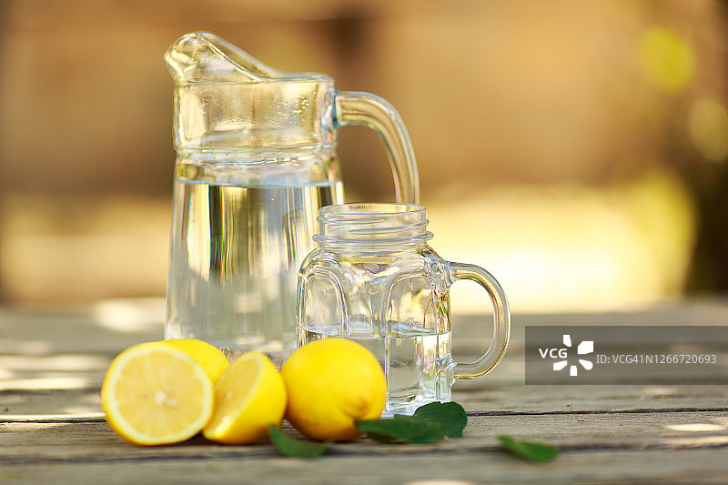 柠檬冷饮排毒饮品，玻璃杯和玻璃罐盛放，户外桌子图片素材