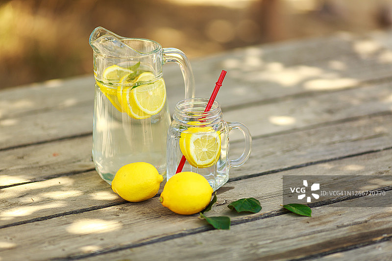 柠檬冷饮排毒饮品，玻璃杯和玻璃罐盛放，户外桌子图片素材