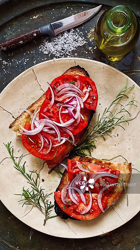 吐司上的新鲜番茄和洋葱，配以迷迭香和橄榄油图片素材
