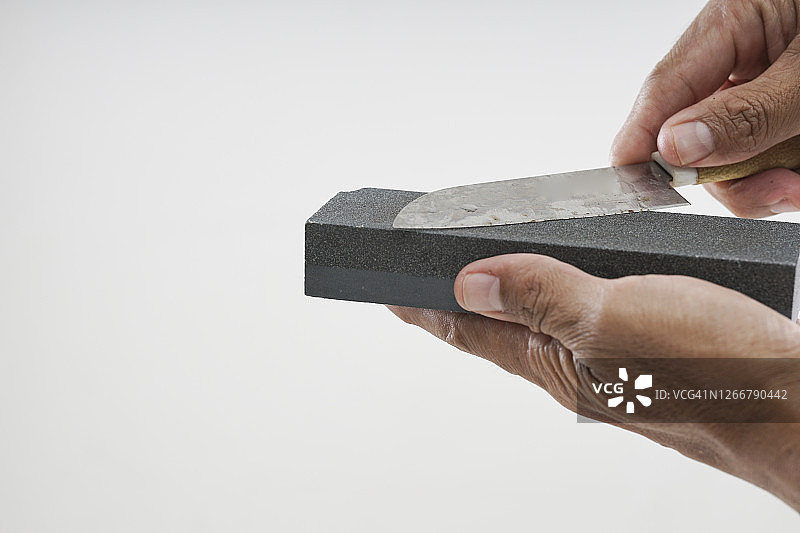 特写镜头下手持磨刀石图片素材