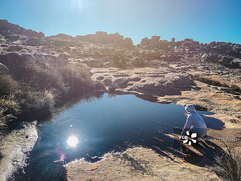 年轻女孩跪在山中岩石水池旁图片素材