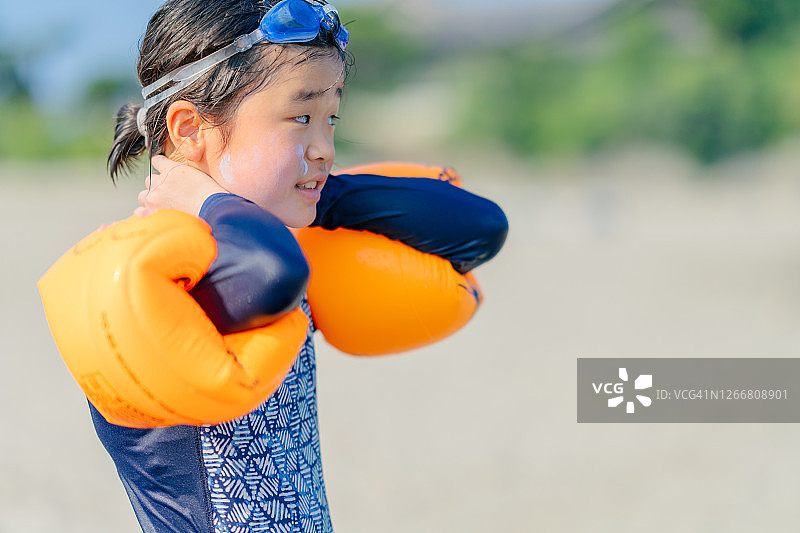 在海滩上涂抹防晒霜的小女孩图片素材