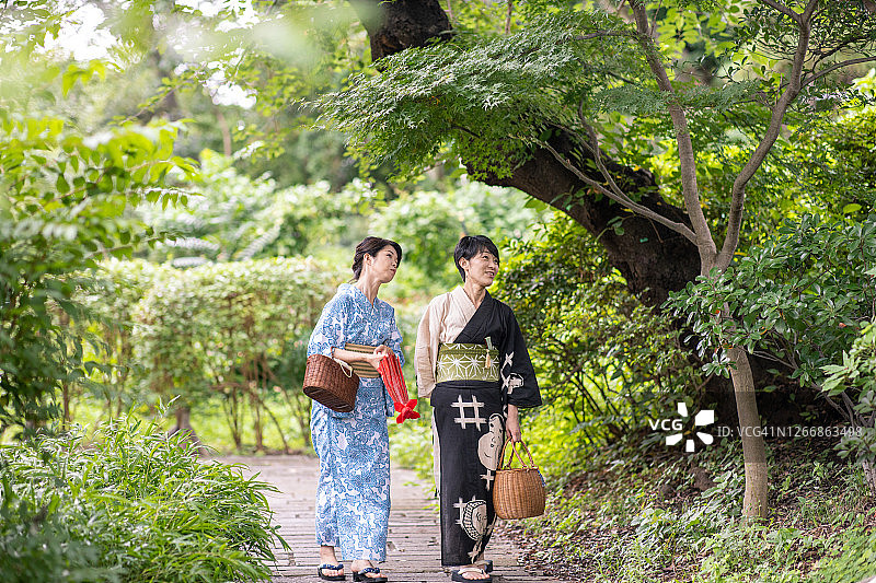 穿着浴衣在日本公园散步欣赏绿色景色的日本女人图片素材
