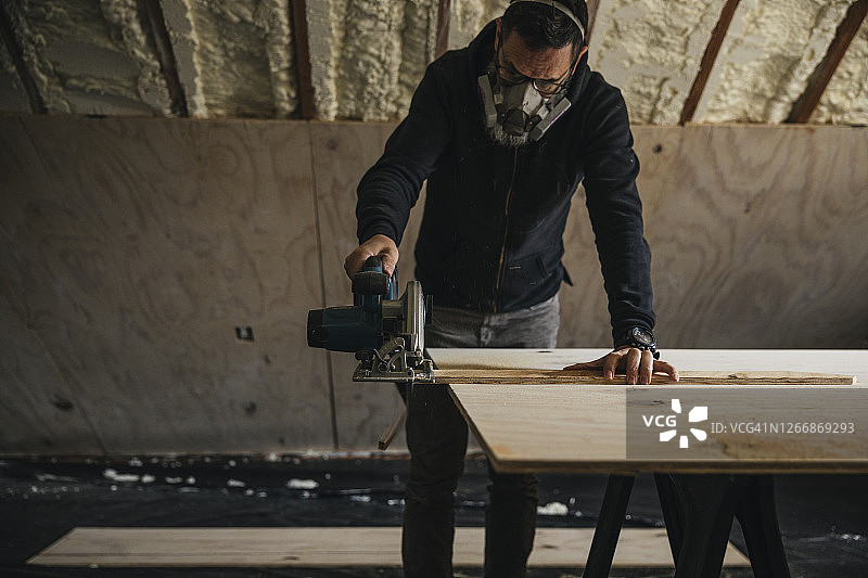 男人翻新旧阁楼时切割胶合板图片素材
