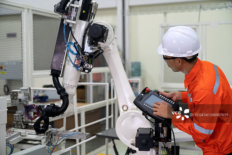 专业技术人员正在对机器人手臂进行编程，以拾取零件并将其放置在智能工厂4.0的正确位置图片素材