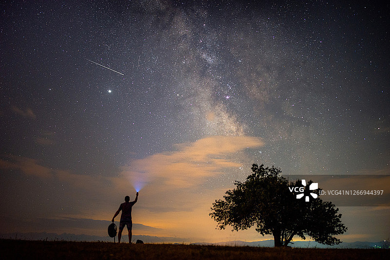 银河系下有明亮流星的男人图片素材