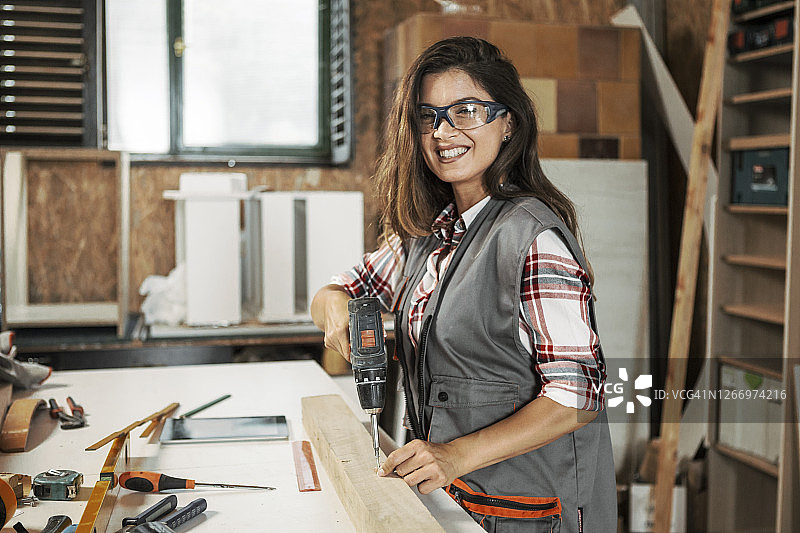 在工作室做木工的年轻女人，看着镜头图片素材