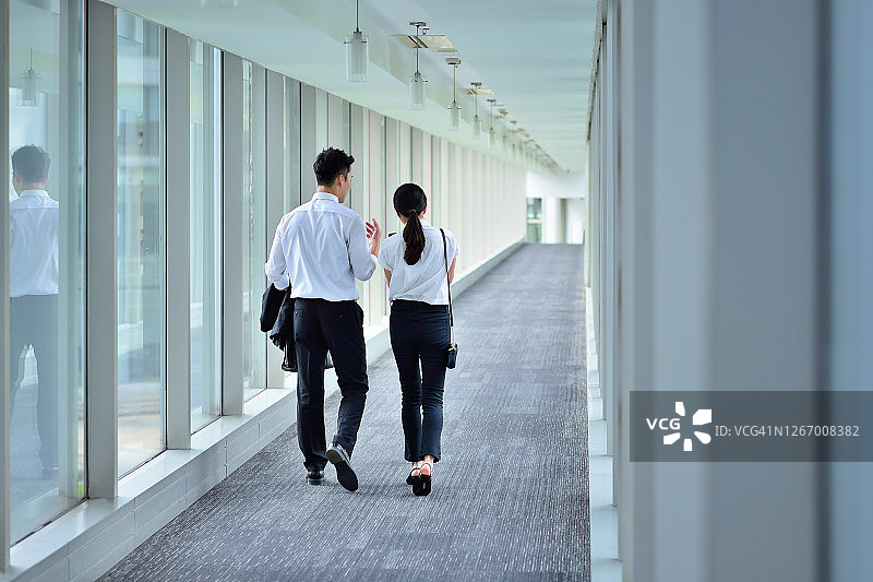 两位同事在通道上交谈和行走的背影图片素材