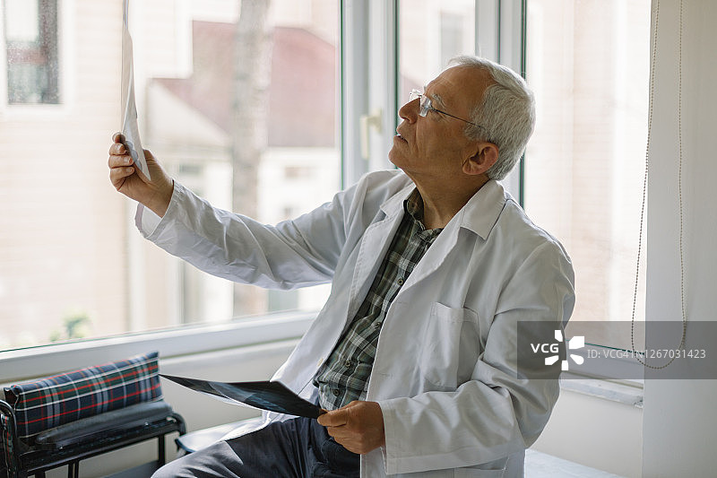 年长的医生正在看病人的X光片图片素材