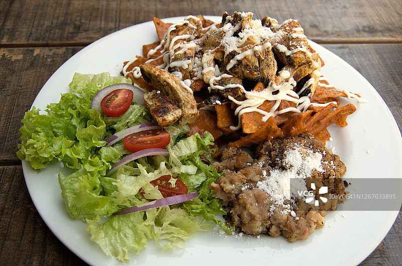 墨西哥玉米片配烤鸡、莎莎酱、炒豆和生菜番茄洋葱沙拉图片素材