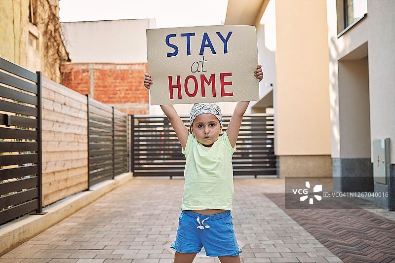 疫情期间，焦虑的孩子举着居家隔离的牌子图片素材